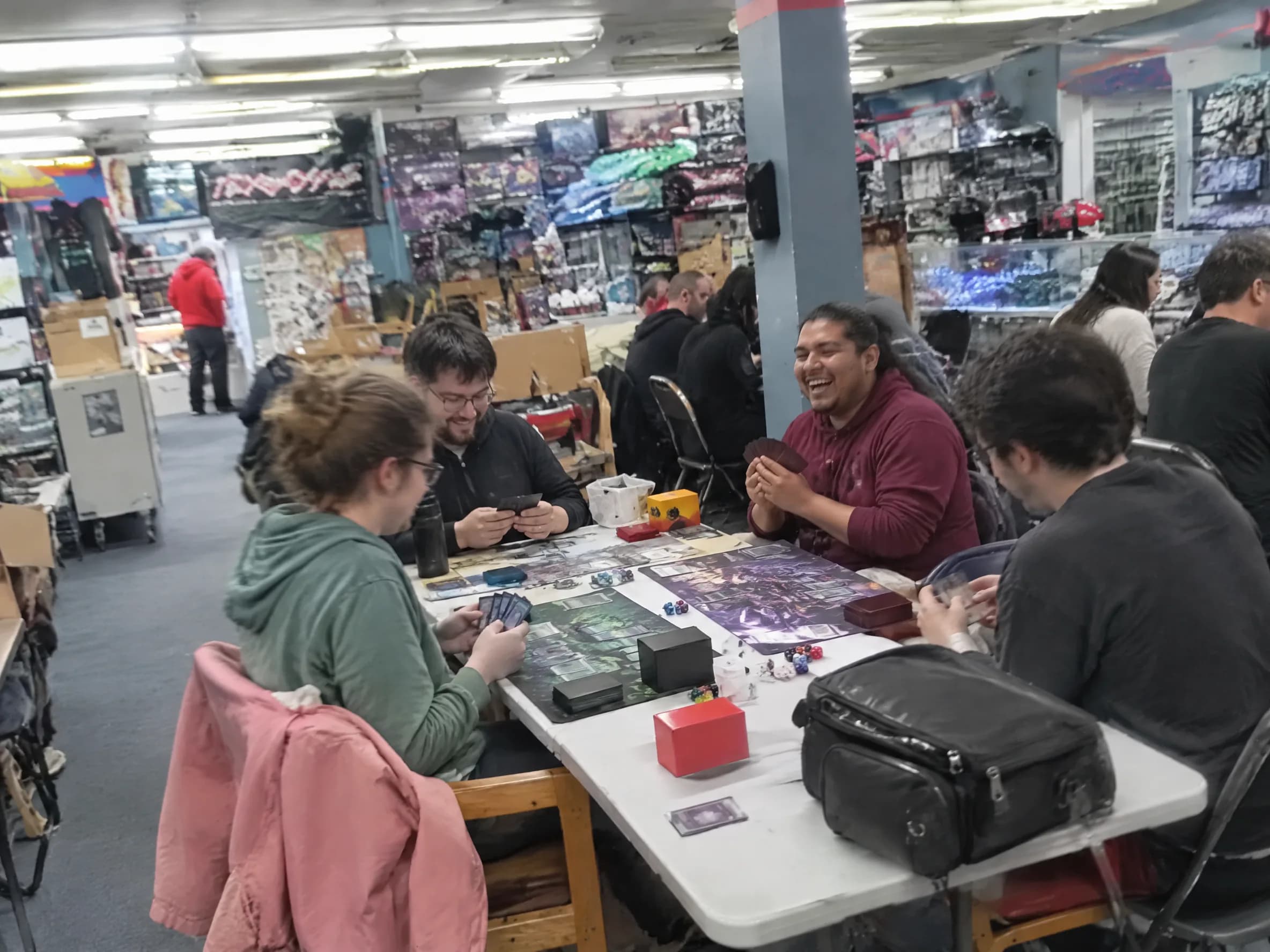 Four players mid-game on playmats during Commander night.