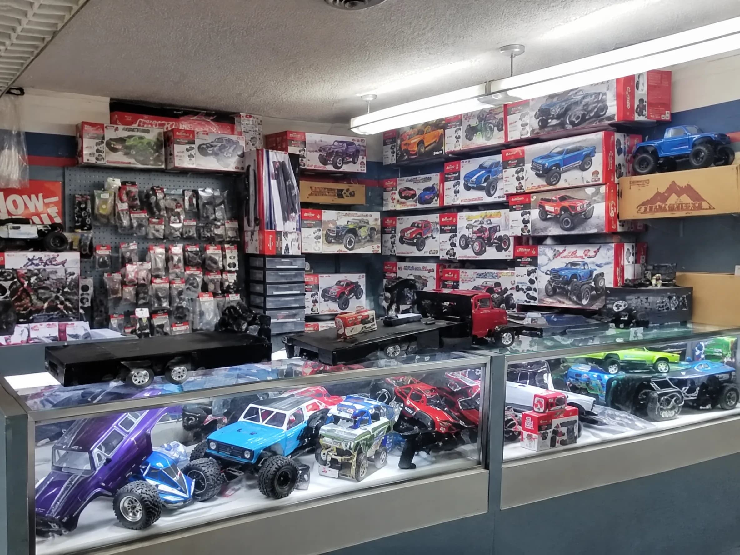 A wall of boxed RC trucks above a case of RC cars.
